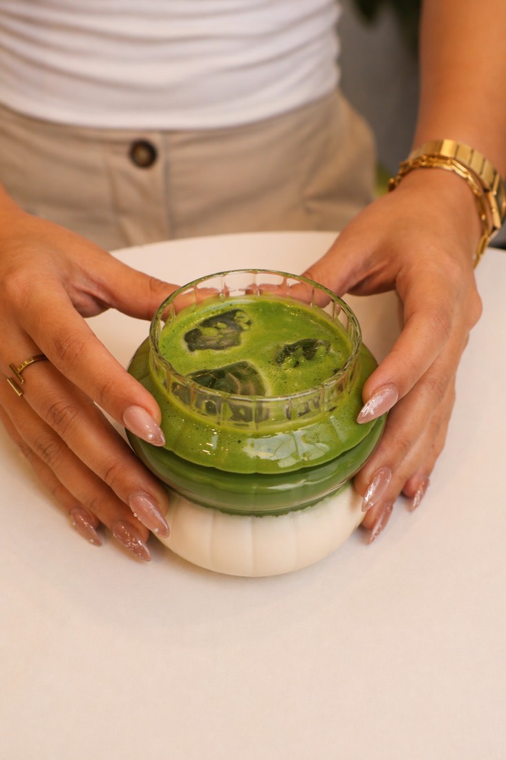 Iced matcha latte held in both hands
